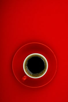 a cup of coffee sitting on top of a saucer next to a red wall