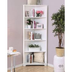 a white book shelf with plants and books on it in a purple living room setting