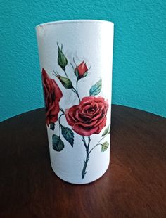 a painted cup sitting on top of a wooden table next to a blue wall in the background