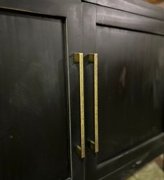 an old black cabinet with brass handles