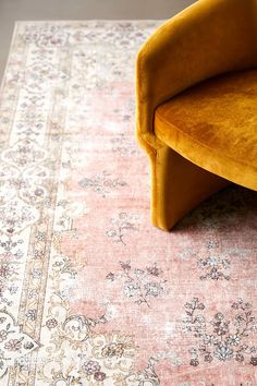 a yellow chair sitting on top of a pink rug