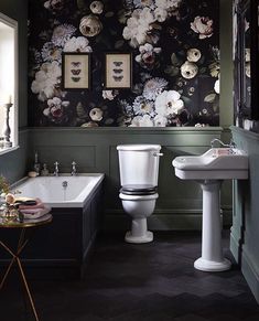 a bathroom with black and white floral wallpaper next to a bathtub, sink and toilet