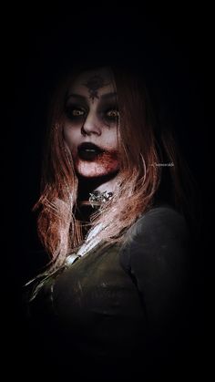 a woman with makeup and blood on her face is standing in the dark, looking at the camera