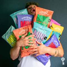 a man with his mouth open holding many bags of candy in front of his face