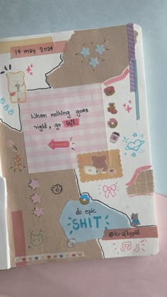 an open book with stickers and writing on the cover, sitting on a pink surface