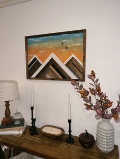 a painting hangs on the wall above a table with candles and other items in front of it