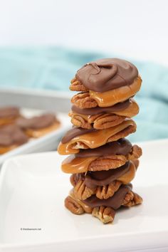 a stack of chocolate covered donuts sitting on top of a white plate with pecans