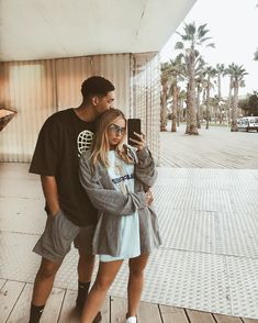 a man standing next to a woman holding a cell phone