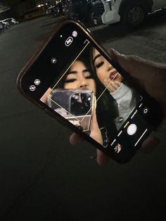 a person holding up a cell phone with an image of two women on the screen