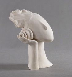 a white ceramic sculpture of a mushroom holding something in it's hand on a gray background