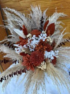 an arrangement of dried flowers and grasses in a vase