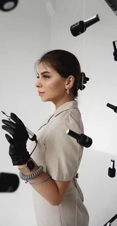 a woman wearing black gloves standing in front of a white wall with lots of lights on it