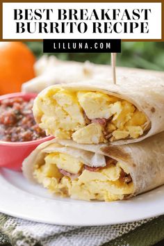 two breakfast burritos on a plate with salsa and an orange in the background