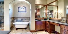 a bath room with a tub a sink and mirrors