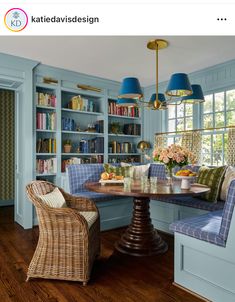 a dining room with blue walls and wooden flooring, built in bookshelves