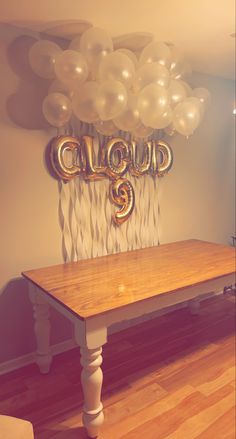 a wooden table with balloons hanging from it's head and the word cloud on top