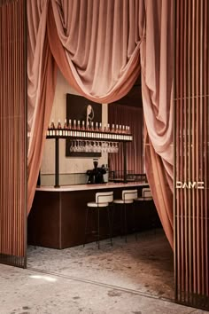 an elegant bar with pink drapes and barstools in the back drop off area