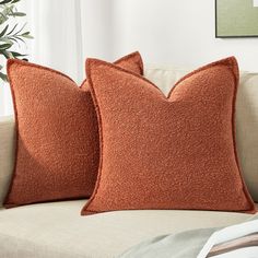 two orange pillows sitting on top of a couch