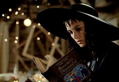 a woman wearing a black hat and holding a book