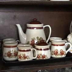 there are many teapots and cups on the shelf next to eachother