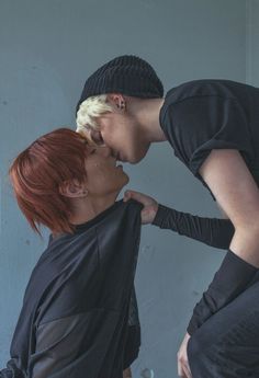 two women with red hair are touching each other's noses while they both wear black clothing