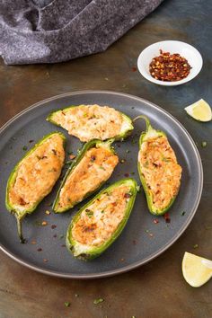 three stuffed jalapenos on a plate next to a bowl of seasoning