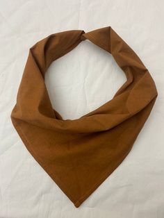 a brown bandana laying on top of a white sheet