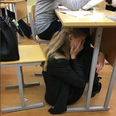 a woman sitting at a table with her head in her hands and another person behind her