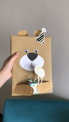 a hand holding a brown paper bag with a bear on it