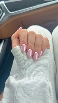 a woman's hand with pink and white nail polish on her nails, sitting in the driver's seat of a car