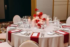 the table is set with white linens and red napkins, silverware, and candles