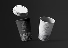 two coffee cups with lids are shown on a black background