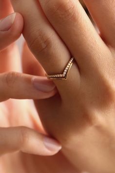 a woman's hand holding a gold ring with three diamonds on the middle finger