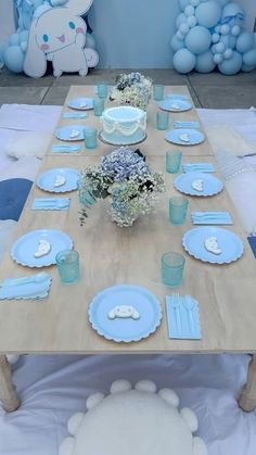 a table set with blue plates and place settings for a baby's first birthday party