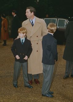 two young boys and an older man standing next to each other in front of a car