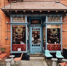 an old brick building with chairs and tables in front of it on the sidewalk outside