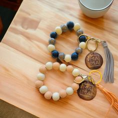 two bracelets with tassels are sitting on a table next to a cup