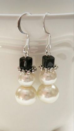 two pearls and black onyxite are hanging from silver earwires