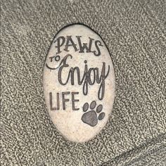 a rock with the words paws to enjoy life written on it