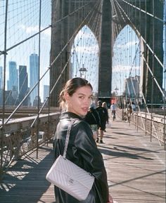 a woman is standing on the bridge with her hand in her pocket and looking at the camera