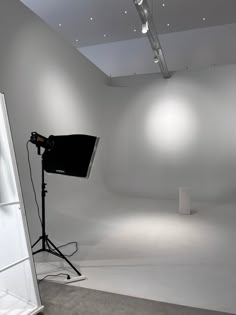 an empty room with white walls and lighting equipment on the floor in front of it