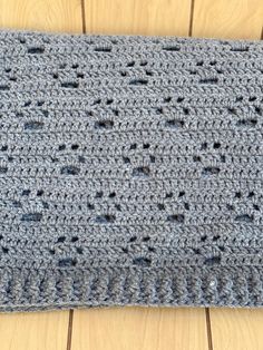 a blue crocheted blanket sitting on top of a wooden floor next to a pair of scissors