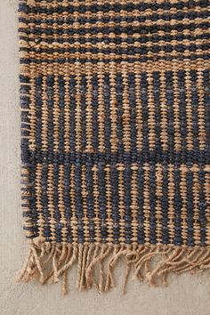 a blue and tan rug with fringes on it's edges, laying on the floor