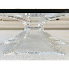 a clear glass coffee table sitting on top of a white carpeted floor next to a couch