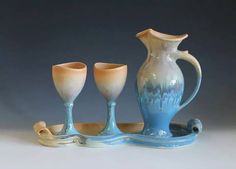 three vases and two goblets are sitting on a tray with a handle