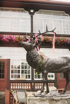 a statue of a deer with flowers on its antlers in front of a building