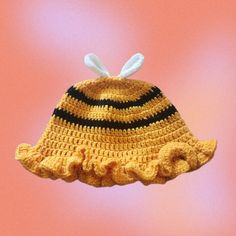 a crocheted yellow hat with black and white bunny ears hanging from it's side