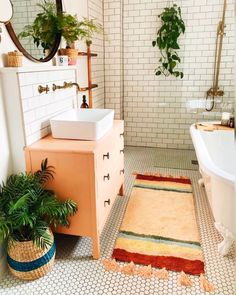 a bath room with a tub a sink and a rug on the floor in front of a mirror