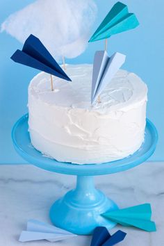 a white cake with blue icing and paper airplanes on top