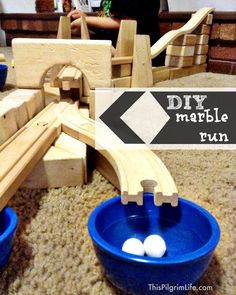 two blue bowls with white balls in them sitting on the floor next to a wooden train track